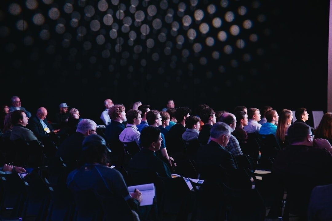 Deltagere sidder samlet til et oplæg i et mørkt konferencerum