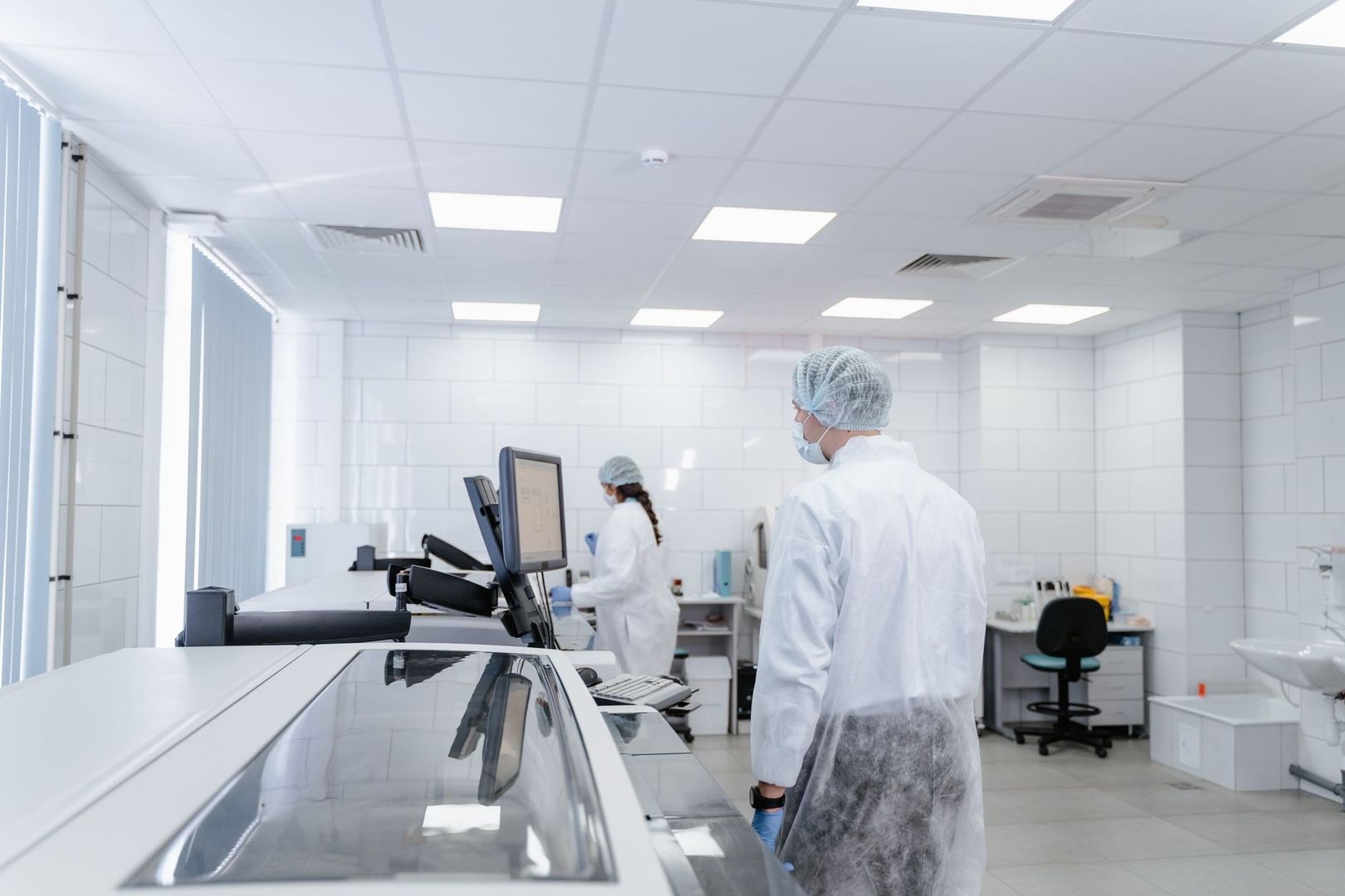 Forskere i beskyttelsesdragter arbejder ved laboratorieudstyr